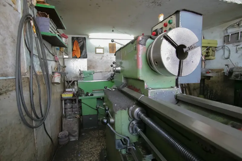 Green lathe in a workshop with tools hanging on the wall